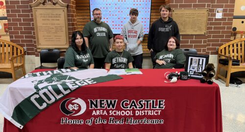 Group photo of female wrestler's letter of intent signing for Bethany College in Commons Area of high school