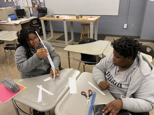 Two design and modeling students working on a paper tower challenge 