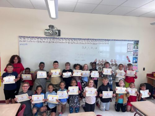 Group photo of Mrs. Relic's class holding their Zearn certificates in the classroom